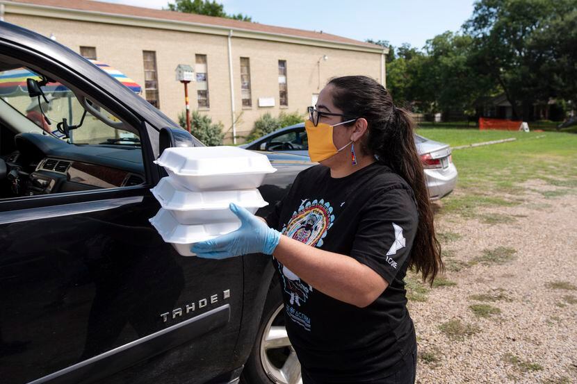 Volunteer Olivia Woodward, of the Caddo people, delivers food to a car during a community...