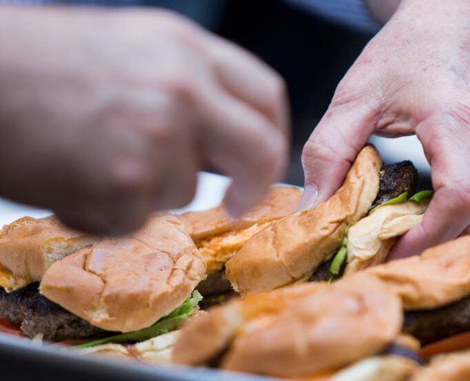 Guests dig into a plate of burgers during a launch party for Chef John Tesar's first book.