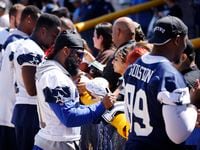 Dallas Cowboys running back Ezekiel Elliott (second from right) signs autographs for...