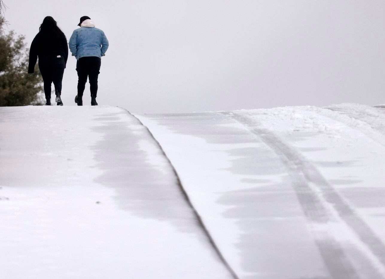 A couple hikes over a sleet-covered hill along N. Cooper St. in Arlington, Texas, January...