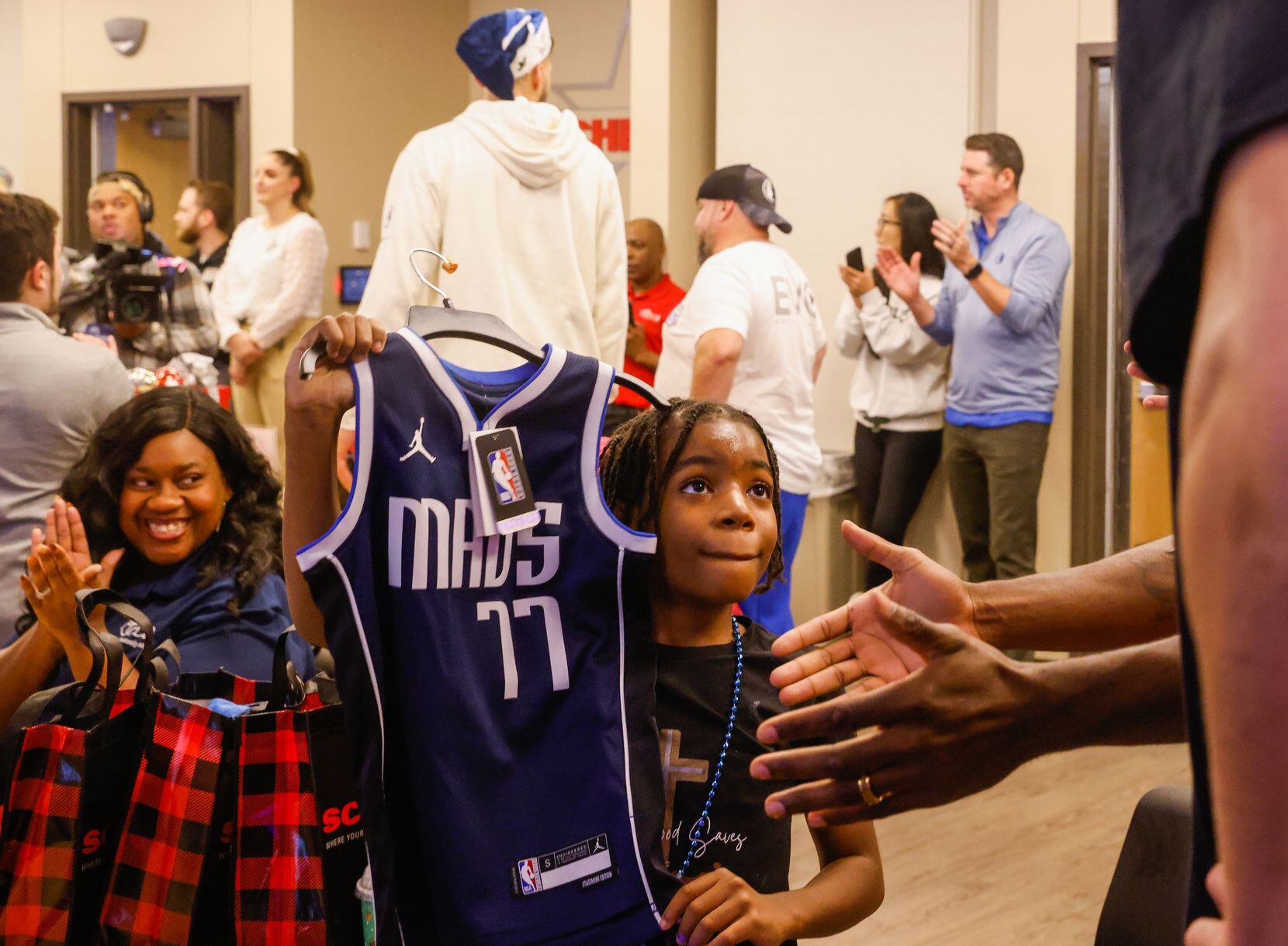 Derrick Givens, Jr. (center), 9, holds his jersey up to show Dallas Mavericks center Dwight...