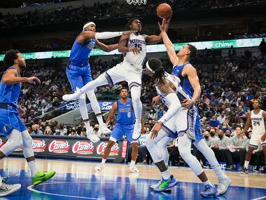 Sacramento Kings guard Davion Mitchell (15) drives to the basket between Dallas Mavericks...