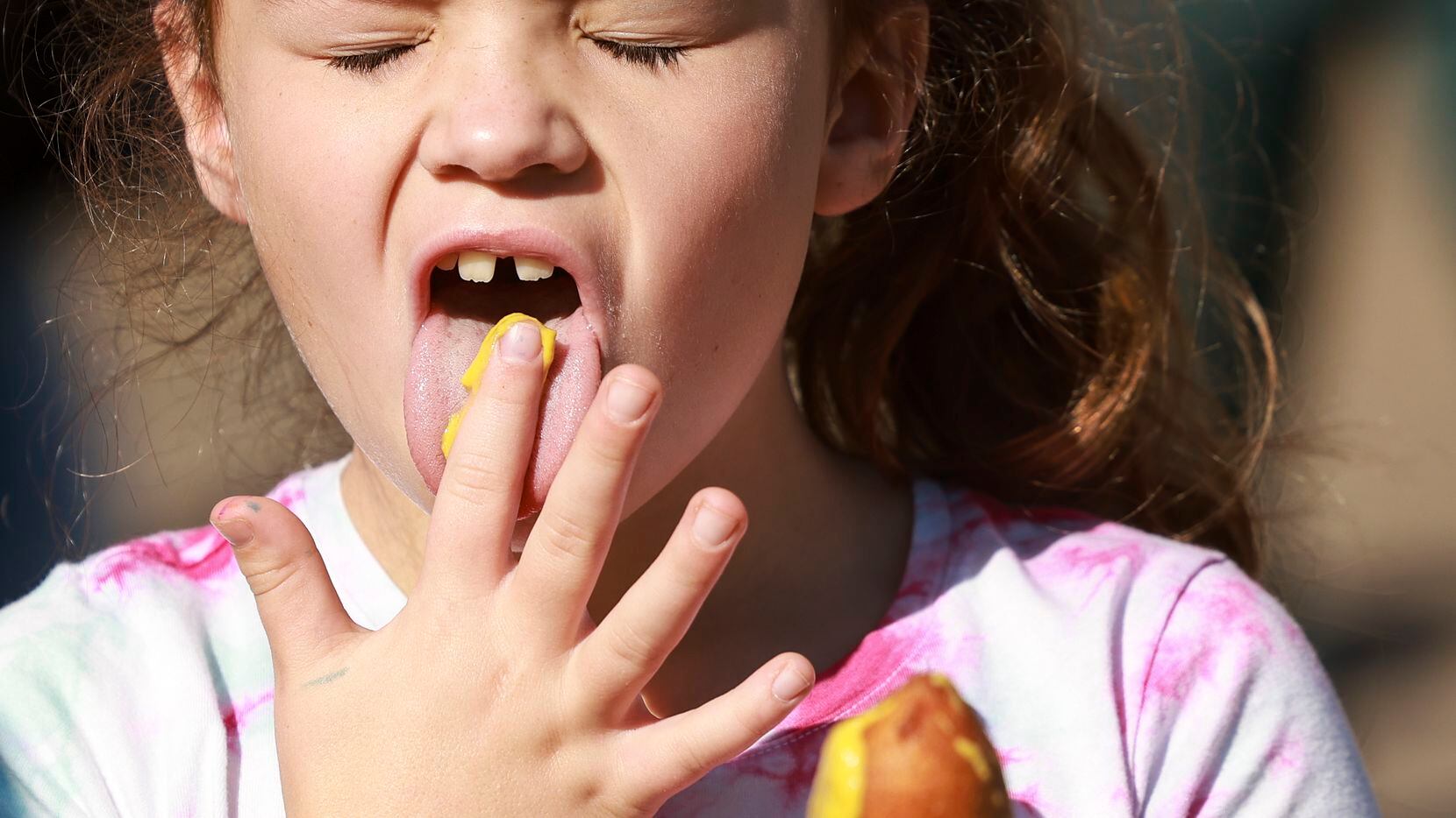 Presleigh Caramela, 7, licks mustard off her fingers after spreading it on her Fletcher’s...
