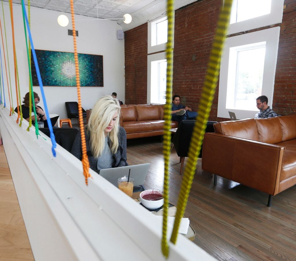 Designer Chandler Mann, foreground, works in the lounge area of the Halcyon Coffee Bar and...