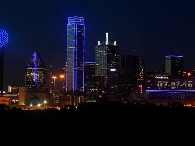 The Omni Dallas Hotel (right) reads "07-07-16" as the skyline of Dallas is aglow in blue.