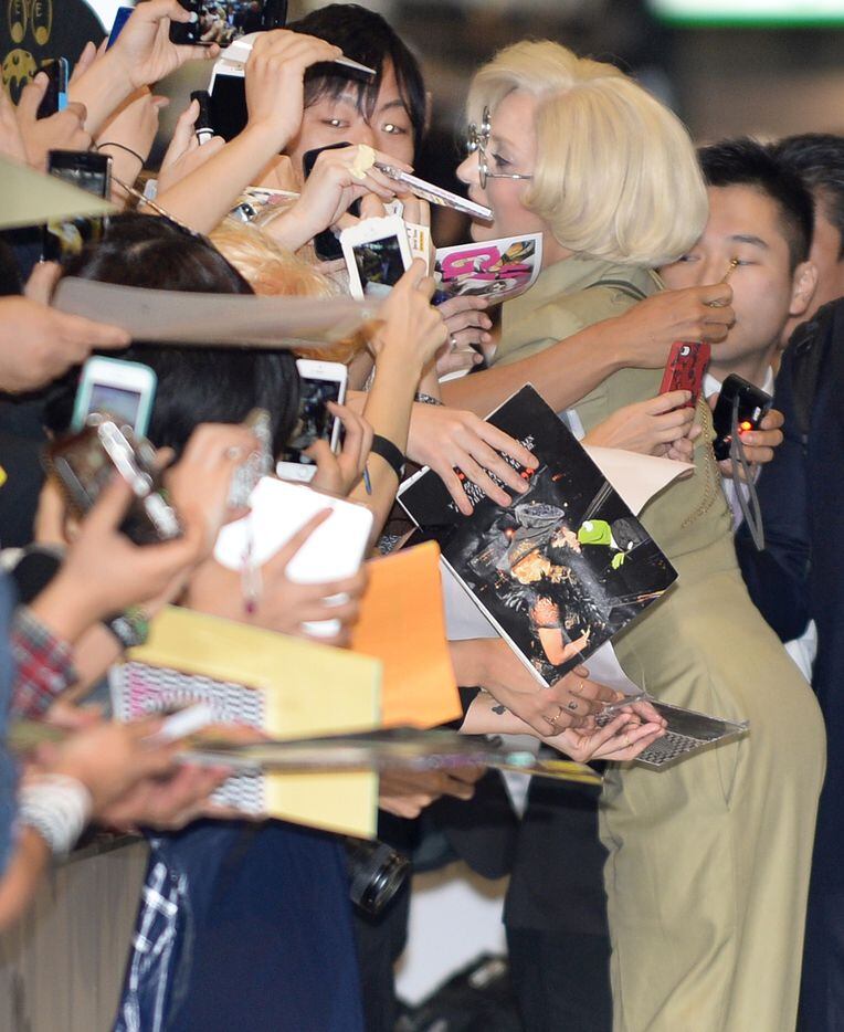 US pop star Lady Gaga (R) hugs a fan as she signs autographs after arriving at Narita...