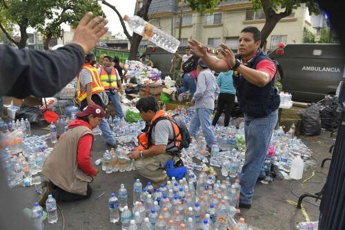 Voluntarios reparten agua mientras continúa la búsqueda de sobrevivientes del simo del...