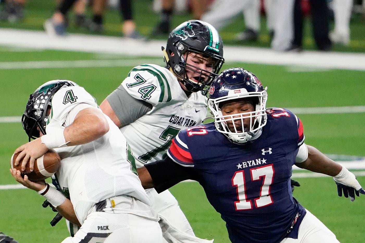 Cedar Park quarterback Ryder Hernandez (4) tries to spin away from Denton Ryan defensive lineman Michael Gee (17) during the second half of the Class 5A Division I state football championship game at AT&T Stadium on Friday, Jan. 15, 2021, in Arlington, Texas. Ryan won the game 59-14. (Smiley N. Pool/The Dallas Morning News)