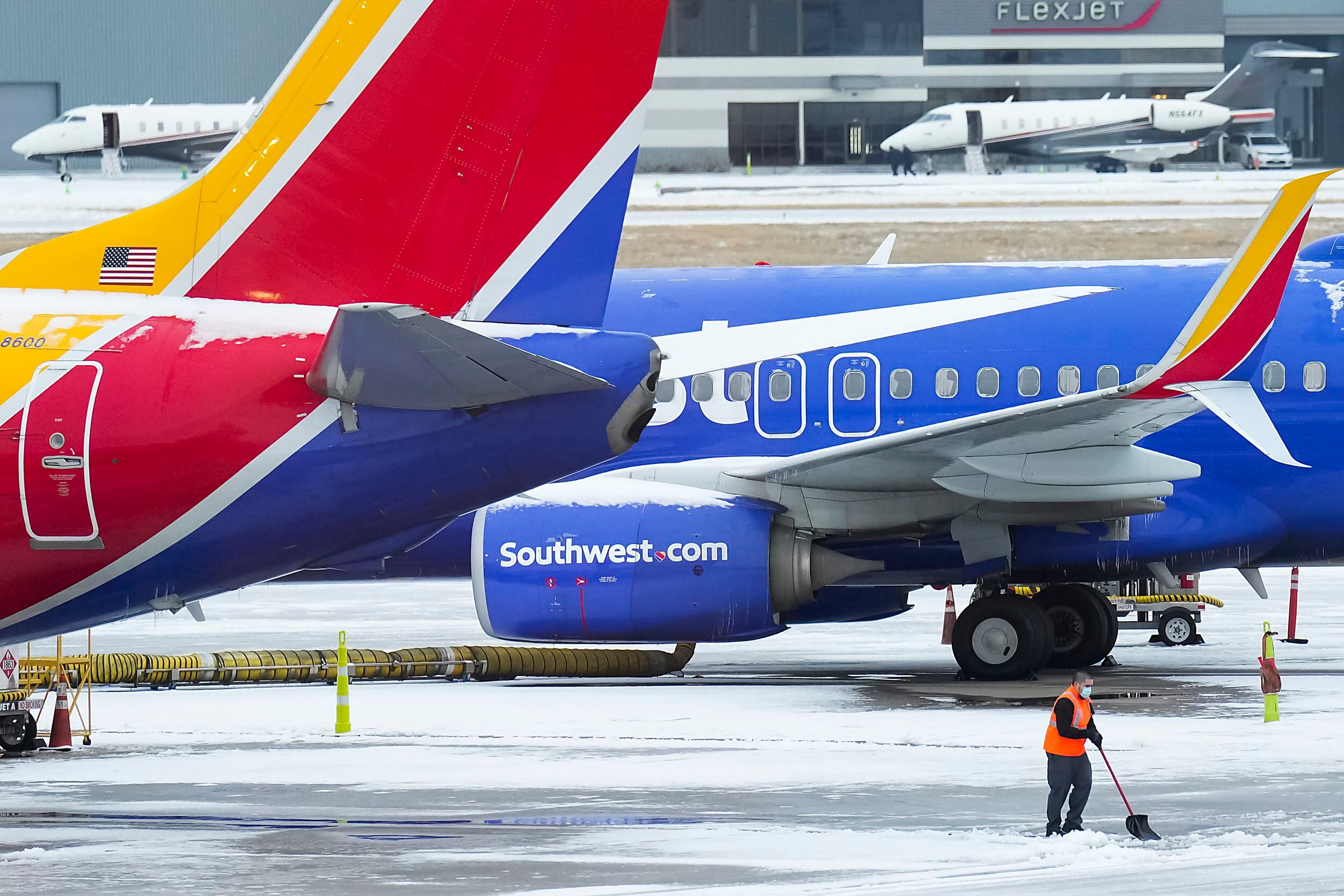 A worker shovels snow on the ramp near Southwest Airlines planes parked at the gates at...