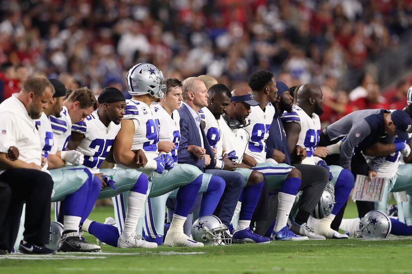 Jugadores y entrenadores de los Cowboys de Dallas se hincan antes del inicio del himno...