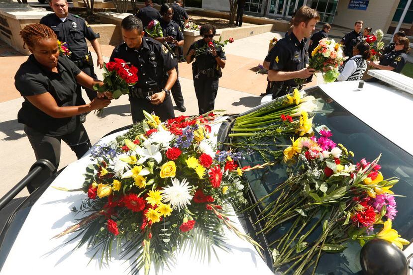 Policías de Dallas mueven flores que fueron dejadas en la estación a un carro en el Jack...
