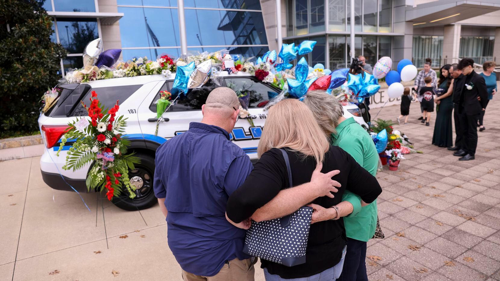 Dennis Nichols (from left) and Melissa Crosby, former elementary school classmates of slain Mesquite Officer Richard Lee Houston II, prayed Saturday with their third-grade teacher, Arlene Myers, in front of a memorial for Houston at the Mesquite Police Department.