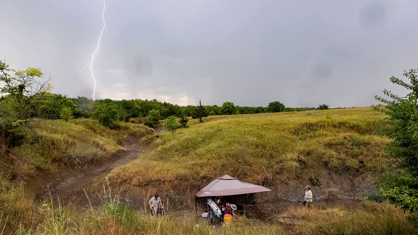 Lightning strikes as a thunderstorm approaches the site where paleontologists and crew from...