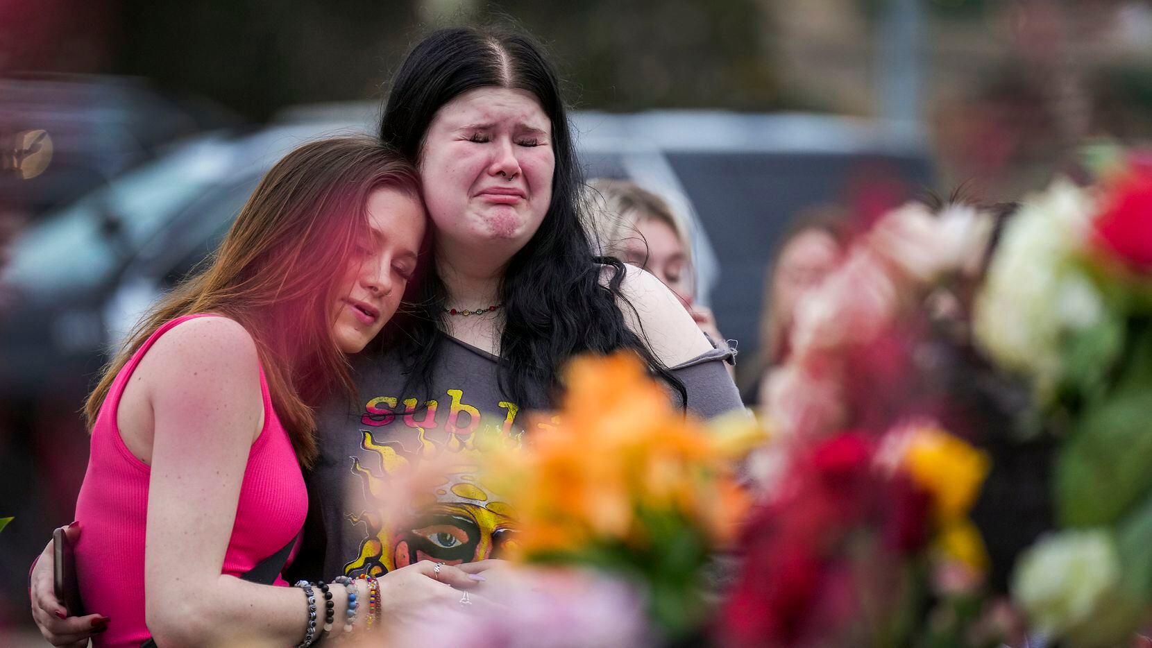 Alexa Keith (center) hugs Brooklyn Deese (left) at a growing memorial outside the mall a day...
