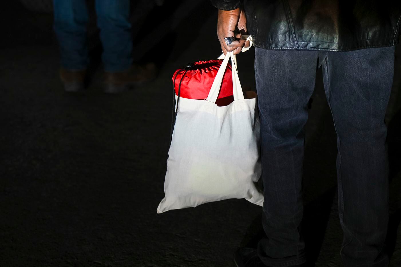 A man experiencing homelessness holds a bag with a blanket and toiletries given to him by...