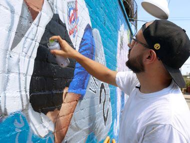 Dallas-based muralist Isaac "IZK" Davies starts to add detail to the mural of the famous...