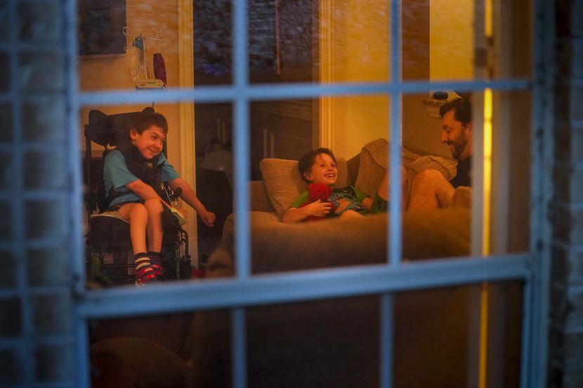Jeff Carlton reads to his sons Scotty (left), 11 and Jeffrey, 9, in the living room of their...