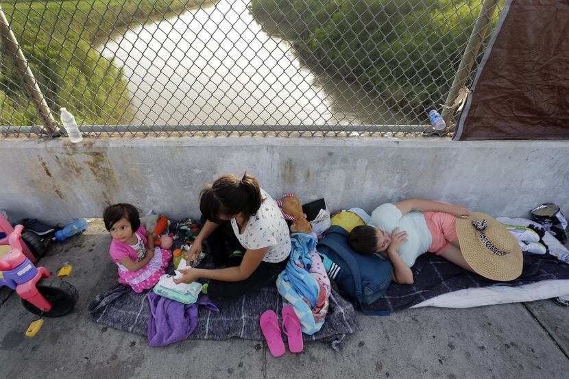 Inmigrantes de Cuba y Guatemala que buscan asilo en Estados Unidos esperan en el Puente...