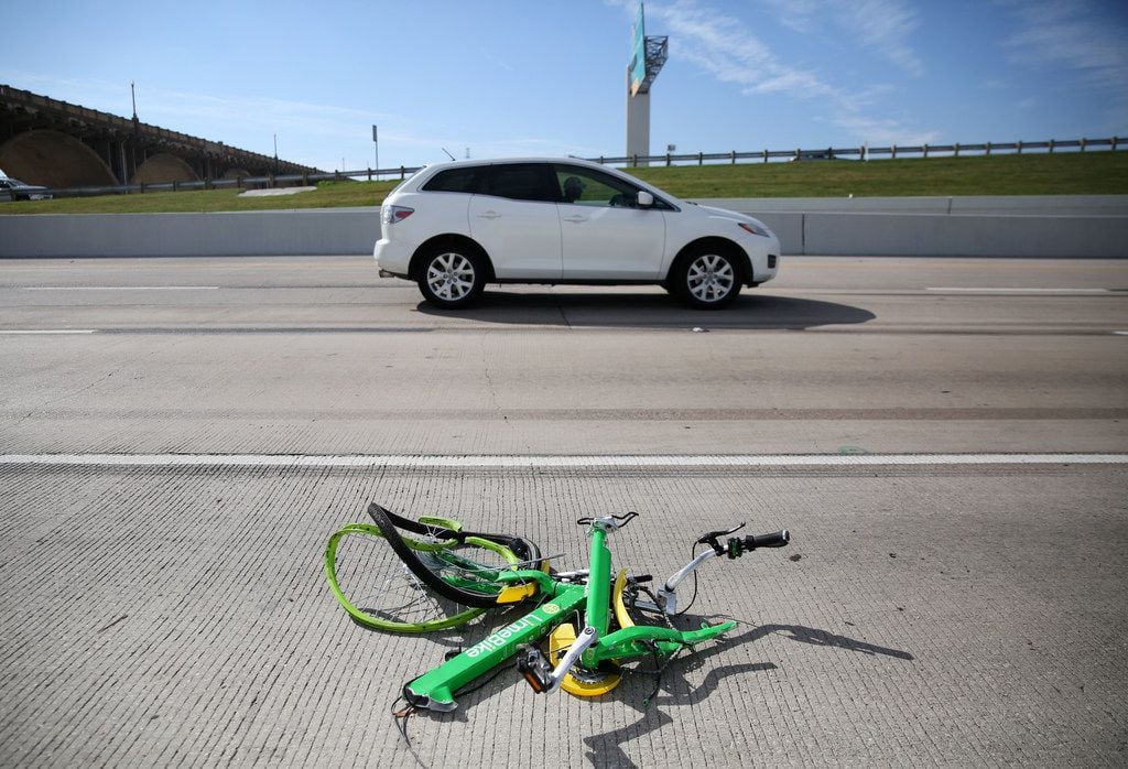The mangled remains of a LimeBike rental bike lie alongside I-35E in downtown Dallas on Nov....