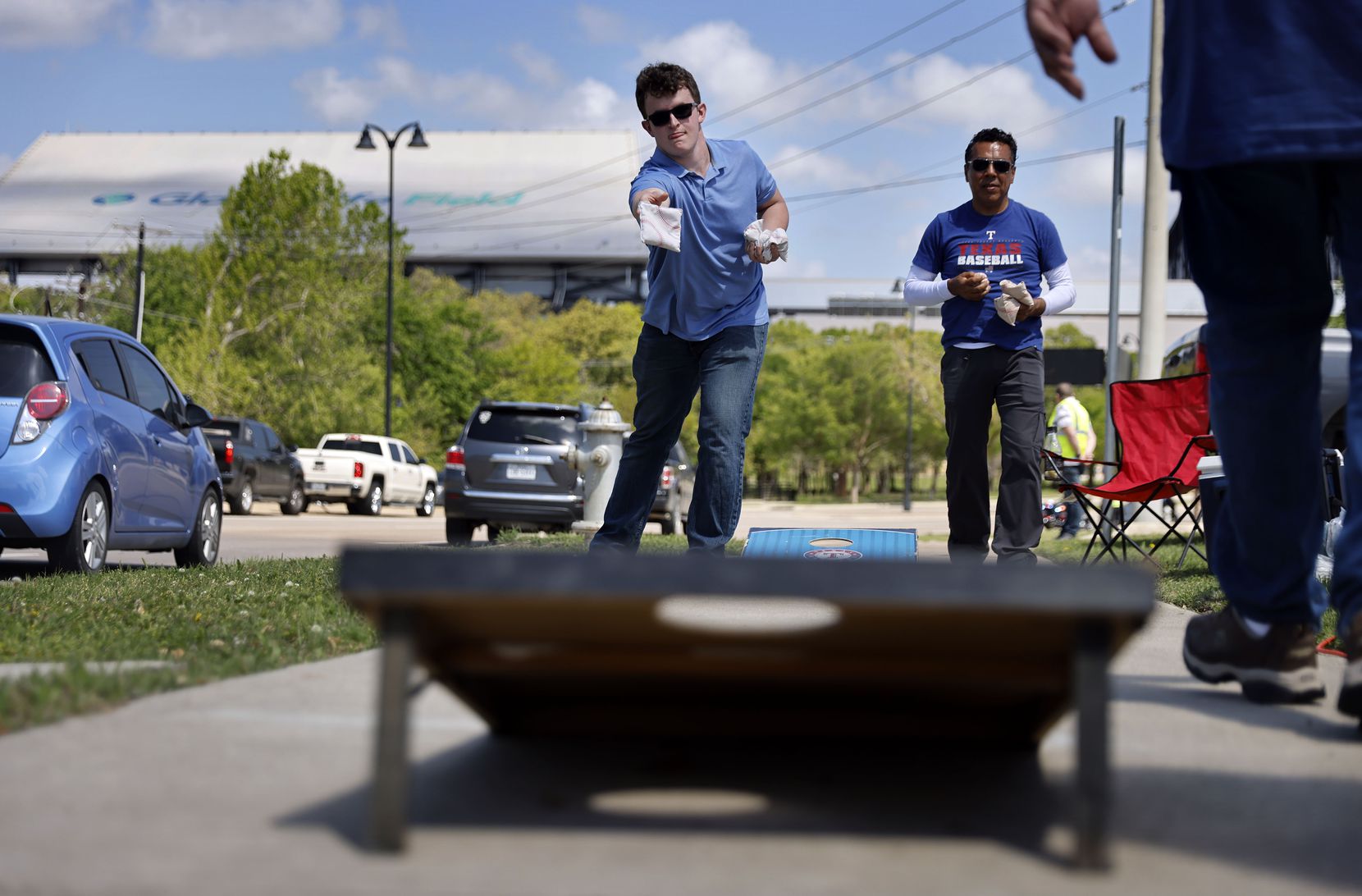 Texas Rangers fans Jack West (left) and Abney Herrera of Pantego play corn hole during an Opening Day tailgate party on private property outside of Globe Life Field in Arlington, Monday, April 5, 2021. The Rangers are facing the Toronto Blue Jays in the home opener. (Tom Fox/The Dallas Morning News)