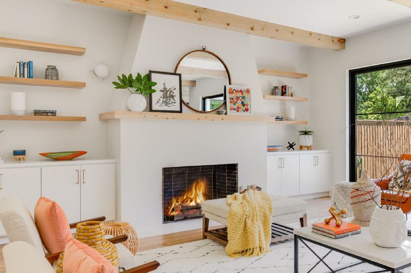 A living room has shelves with minimal decor and a fire in the fireplace.
