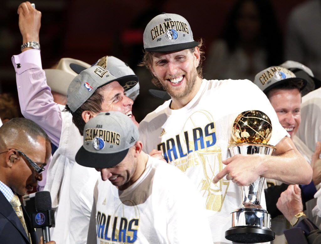 FILE - Dallas Mavericks power forward Dirk Nowitzki (41) holds the Bill Russell NBA Finals MVP trophy as he, owner Mark Cuban, and others celebrate after the Mavs won the NBA Championship by winning game six of the NBA Finals against the Miami Heat at American Airlines Arena in Miami, Florida, June 12, 2011.