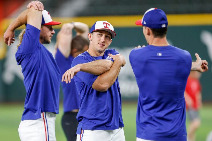 Texas Rangers outfielder Wyatt Langford (center) stretches with teammates during a practice...