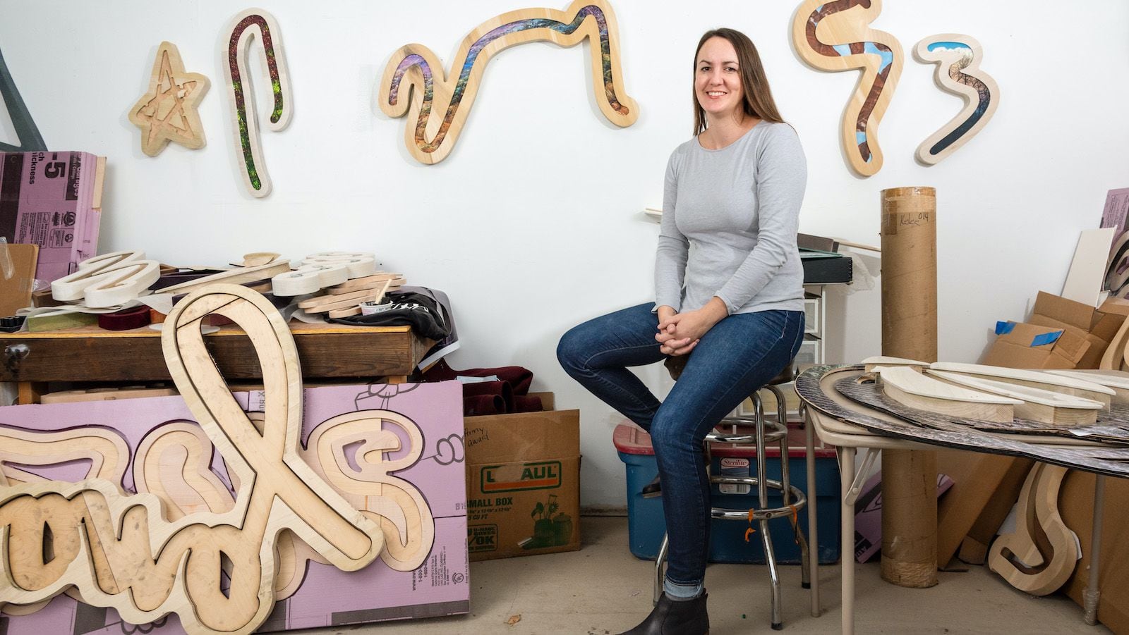 Artist Kaylee Appleton sits in her studio, surrounded by her work.