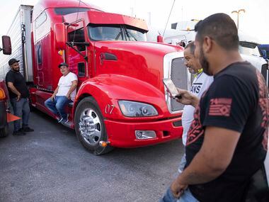 Truck drivers Ignacio Arceo (left) and Carlos Cabrera (center) chat with other drivers at a...