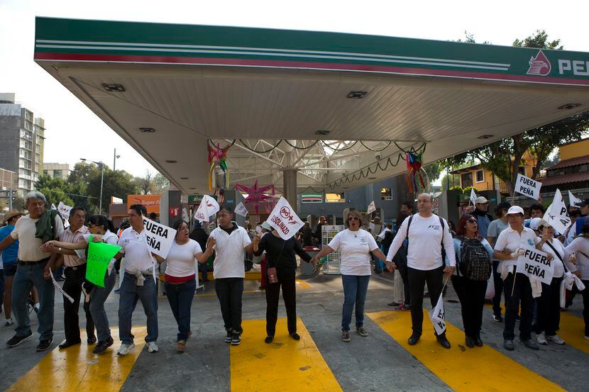 Personas forman una cadena humana en una gasolinera en la Ciudad de México para protestar...