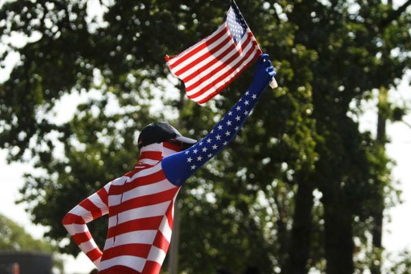 Dressed in a flag-like full-body suit, a performer carries the American Flag during the City...