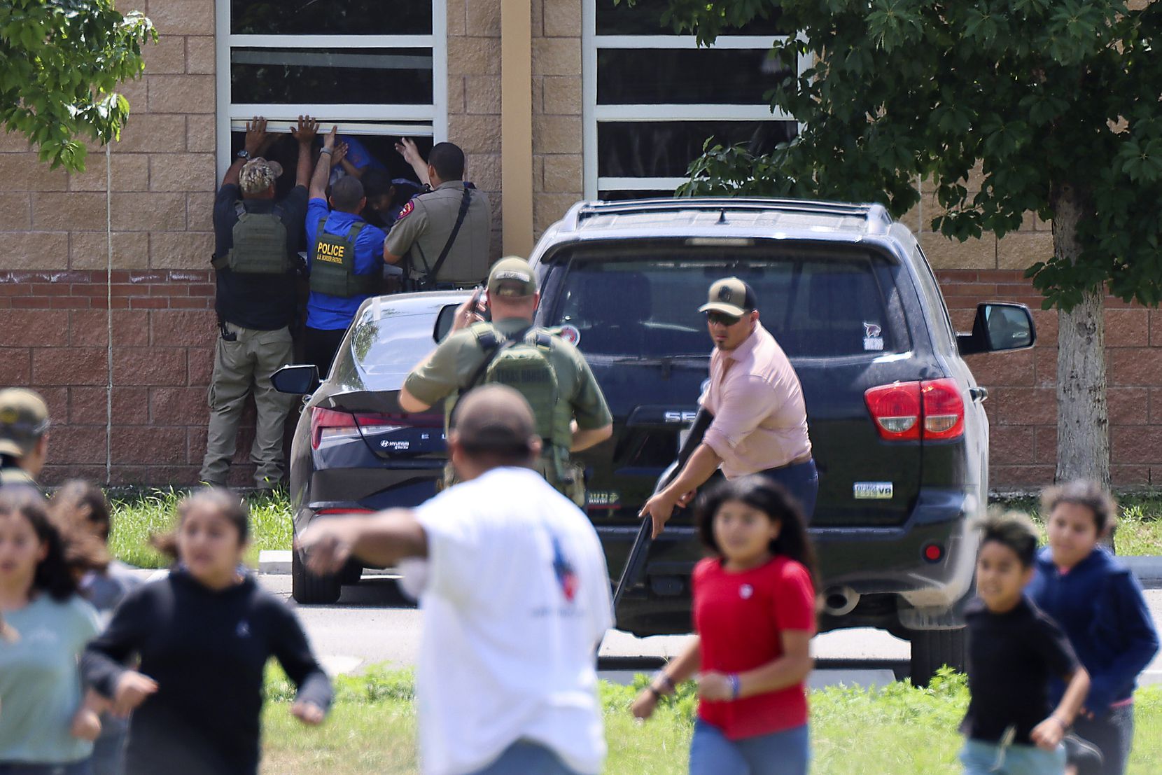 School children are evacuated by law enforcement officers through classroom windows in a...