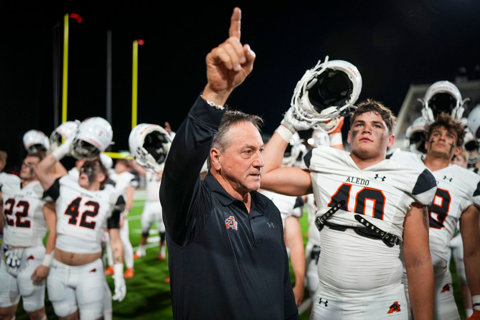 Aledo head coach Tim Buchanan stands for the school song with his players after a victory...