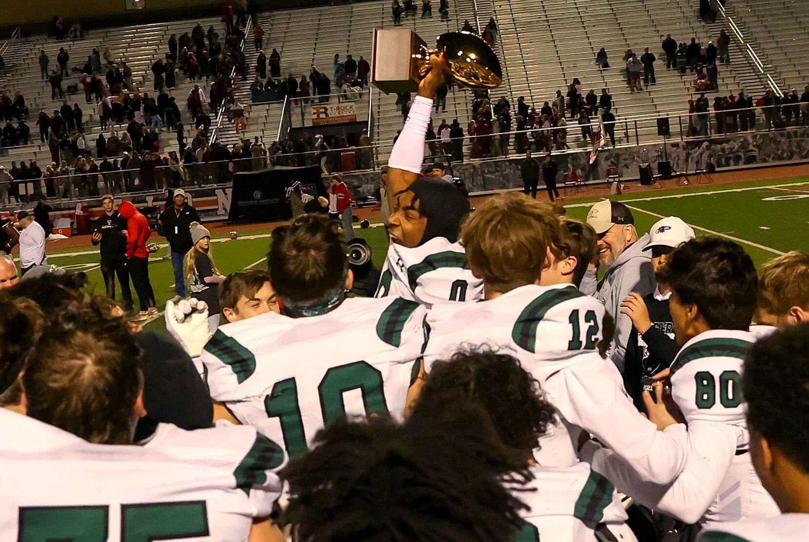 Prosper wide receiver Tyler Bailey (0) holds up the trophy after beating Flower Mound...