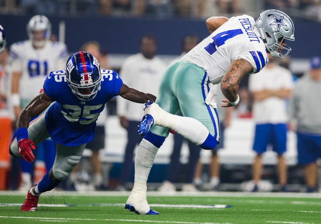 Dallas Cowboys quarterback Dak Prescott (4) is tripped up by New York Giants cornerback...