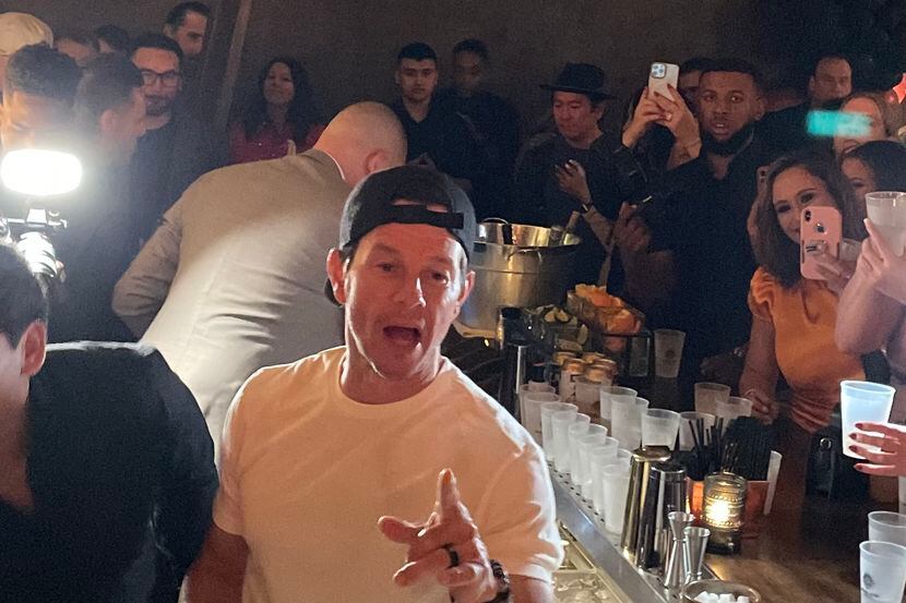 Mark Wahlberg pours tequila for fans behind the bar at La Neta in Dallas on March 2, 2023.