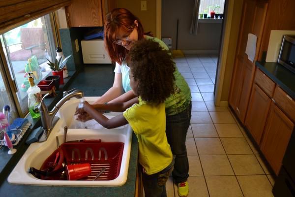 
Kimmy (back) and her oldest daughter wash their hands before dinner at Emily’s Place, a...