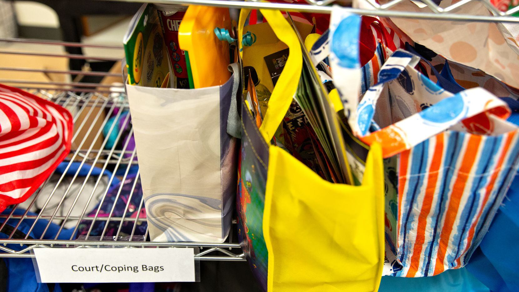 Amid a supply closet filled with clothes and toys, a shelf of "court/coping bags" is a stark...