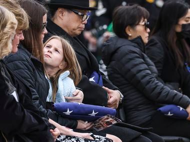 Kinsley Stout looks up at her mother Brittany after she is handed an American flag in memory...