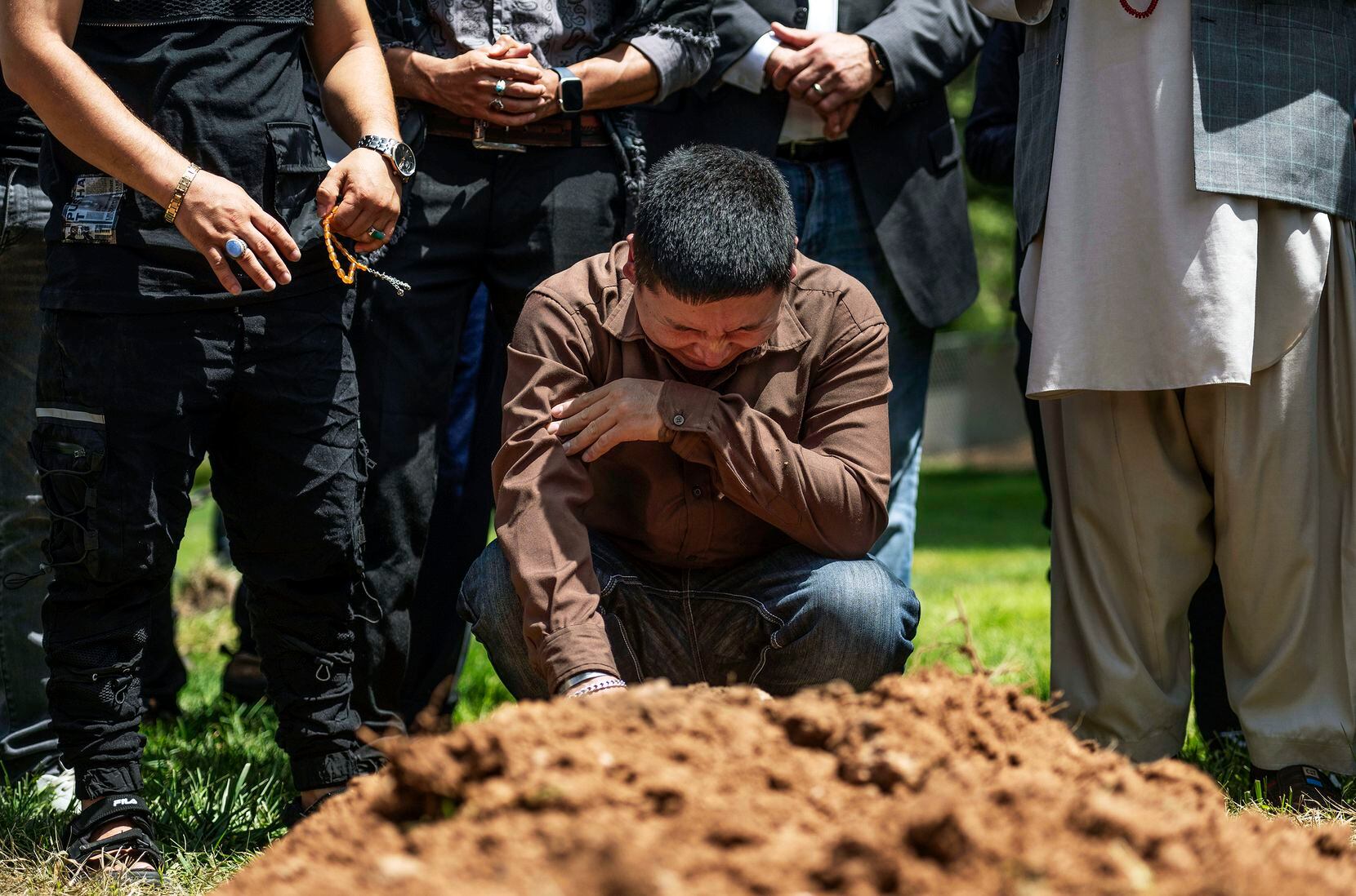 Altaf Hussain cries over the grave of his brother Aftab Hussein at Fairview Memorial Park in...