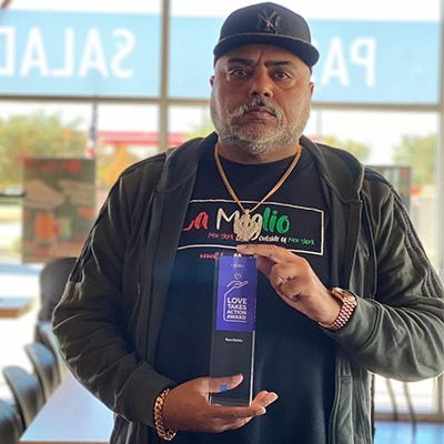 Ram Mehta, owner of In-Fretta pizza in Plano, holds a "Love Takes Action Award"  he received in 2020 from the New York Life Foundation for his charitable work.