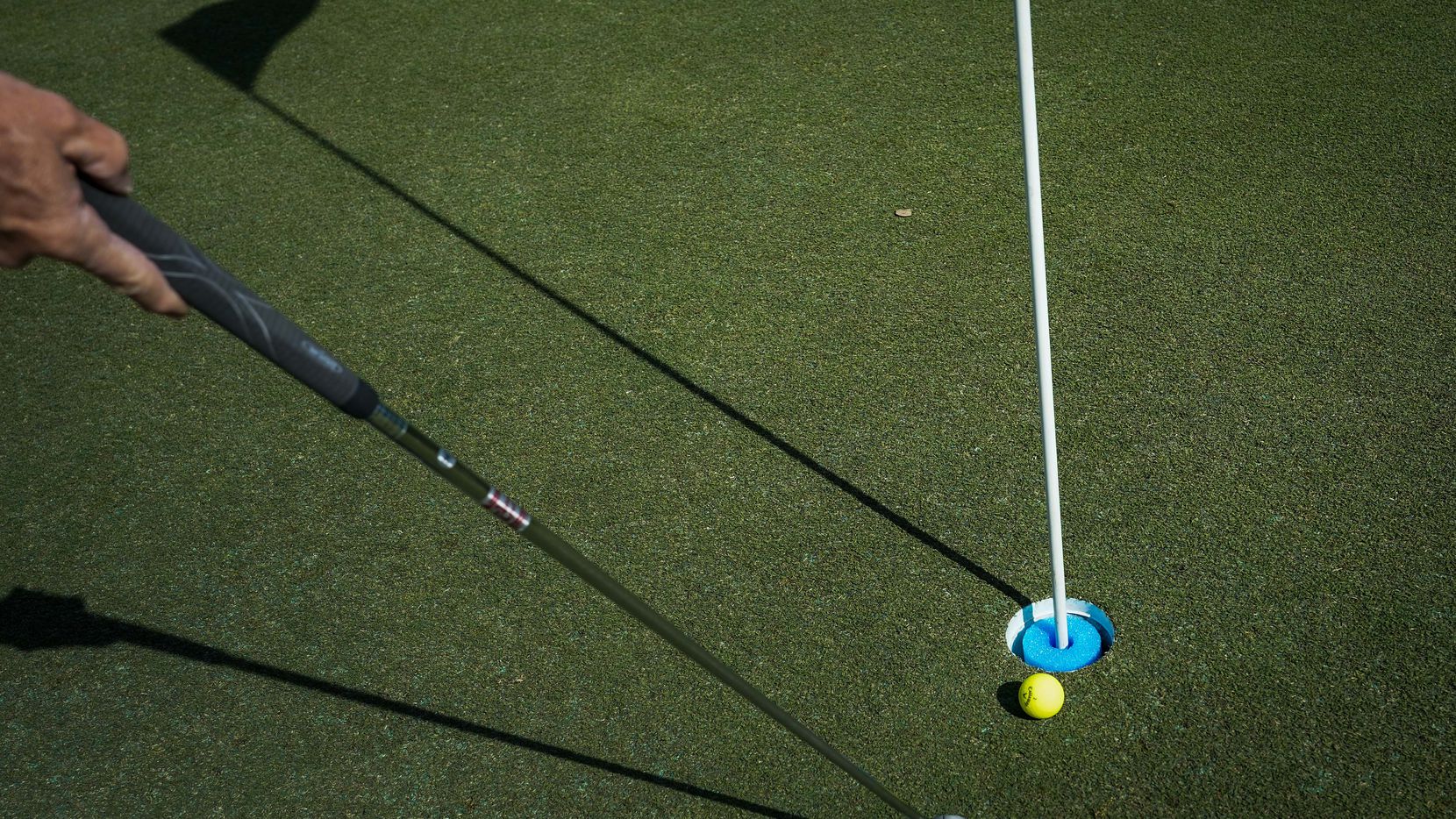 A golfer taps in a put on the first green at Golf Club of Dallas on Wednesday, April 1, 2020, in Dallas. Due to coronavirus concerns, pin flags remain in place and a foam ring keeps balls from falling all the way into the cup.  Rakes for sand traps and sand bottles have also been removed from the course.