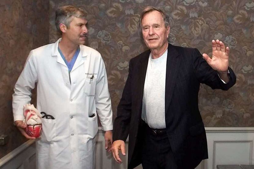 Former President George Bush, right, waves as he leaves with cardiologist Mark Hausknecht...