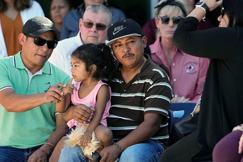 Mass shooting survivor Wilson Garcia, center, holds a young girl during a vigil for his son...