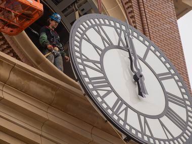 Workers from MEI Rigging & Crating work to install a 12-foot glass clock on the Grapevine...