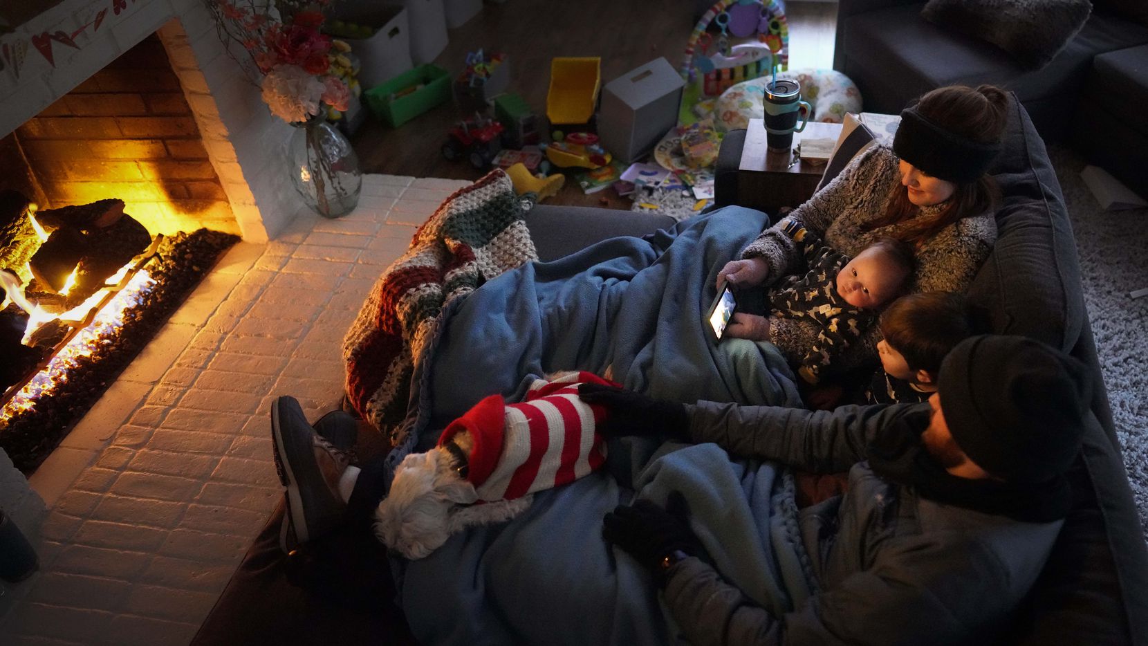 Dan Bryant and his wife Anna huddle by the fire with sons Benny, 3, and Sam, 12 weeks, along...