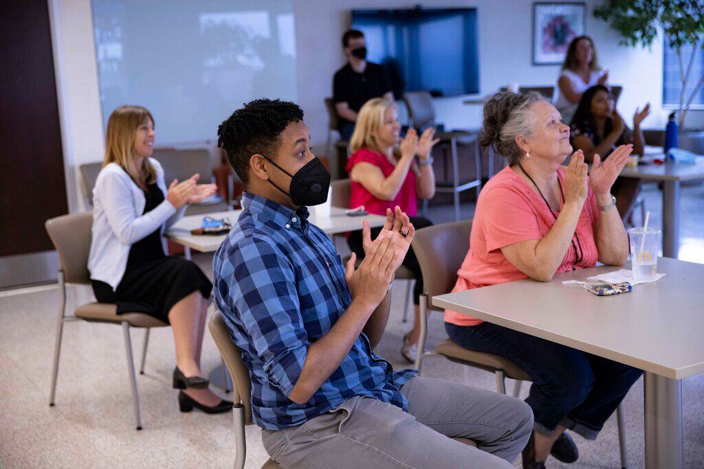 Employees clap during a monthly company meeting on Aug. 17 at the International Risk Management Institute office in Dallas.