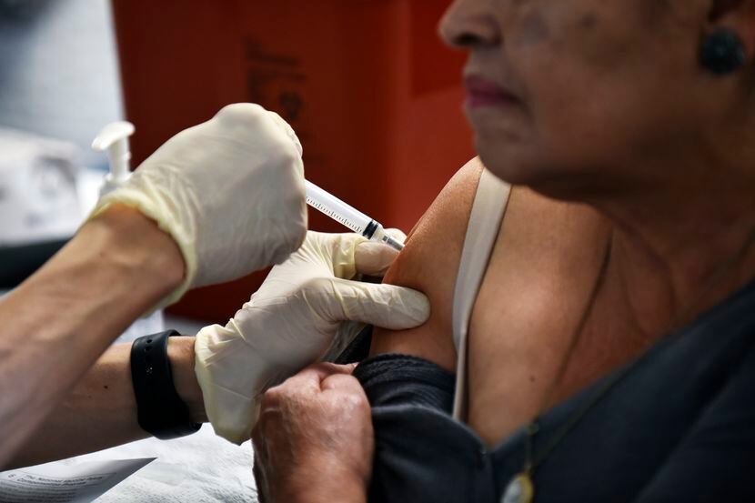 En esta foto de archivo se ve a una mujer hispana recibe la vacuna contra la influenza en...