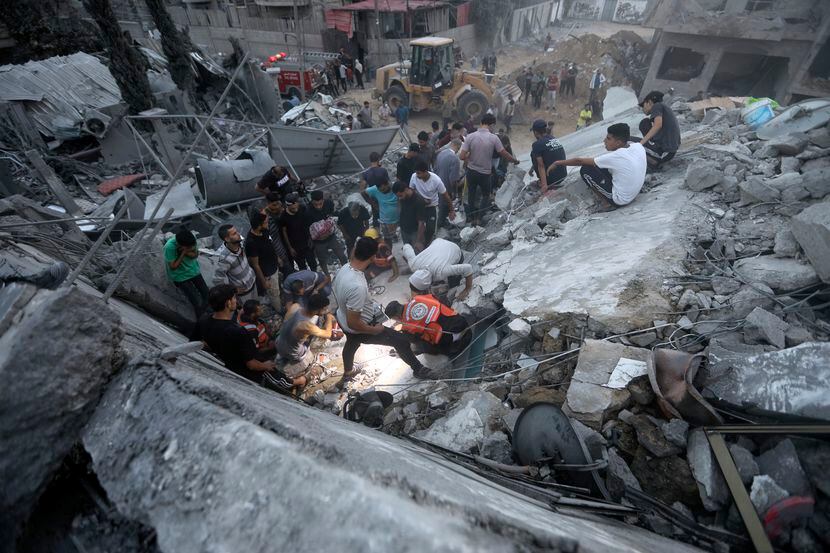 Palestinians look for survivors under the rubble of a destroyed building following Israeli...