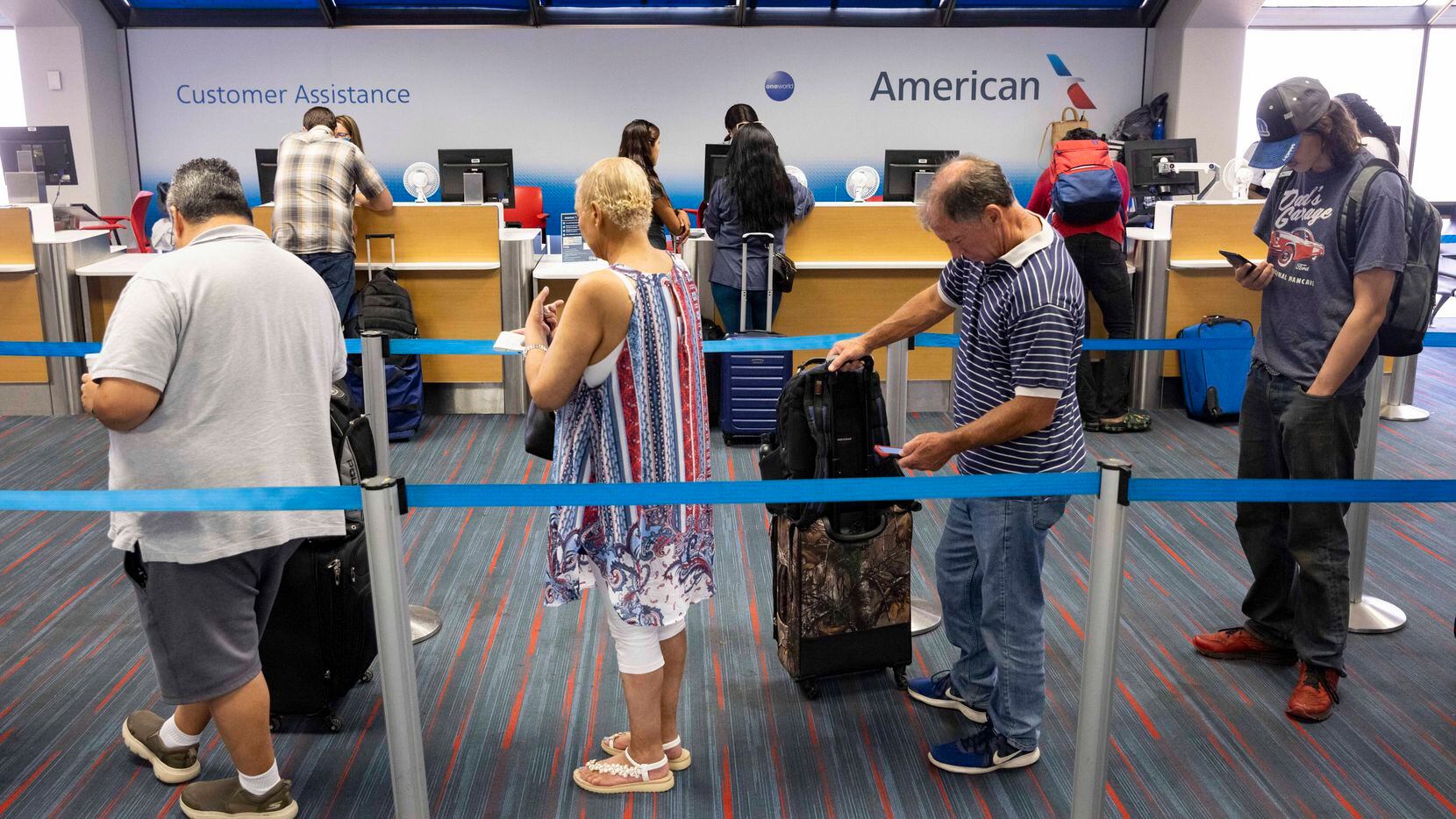 Passengers wait to talk to American Airlines customer assistance representatives in Terminal...